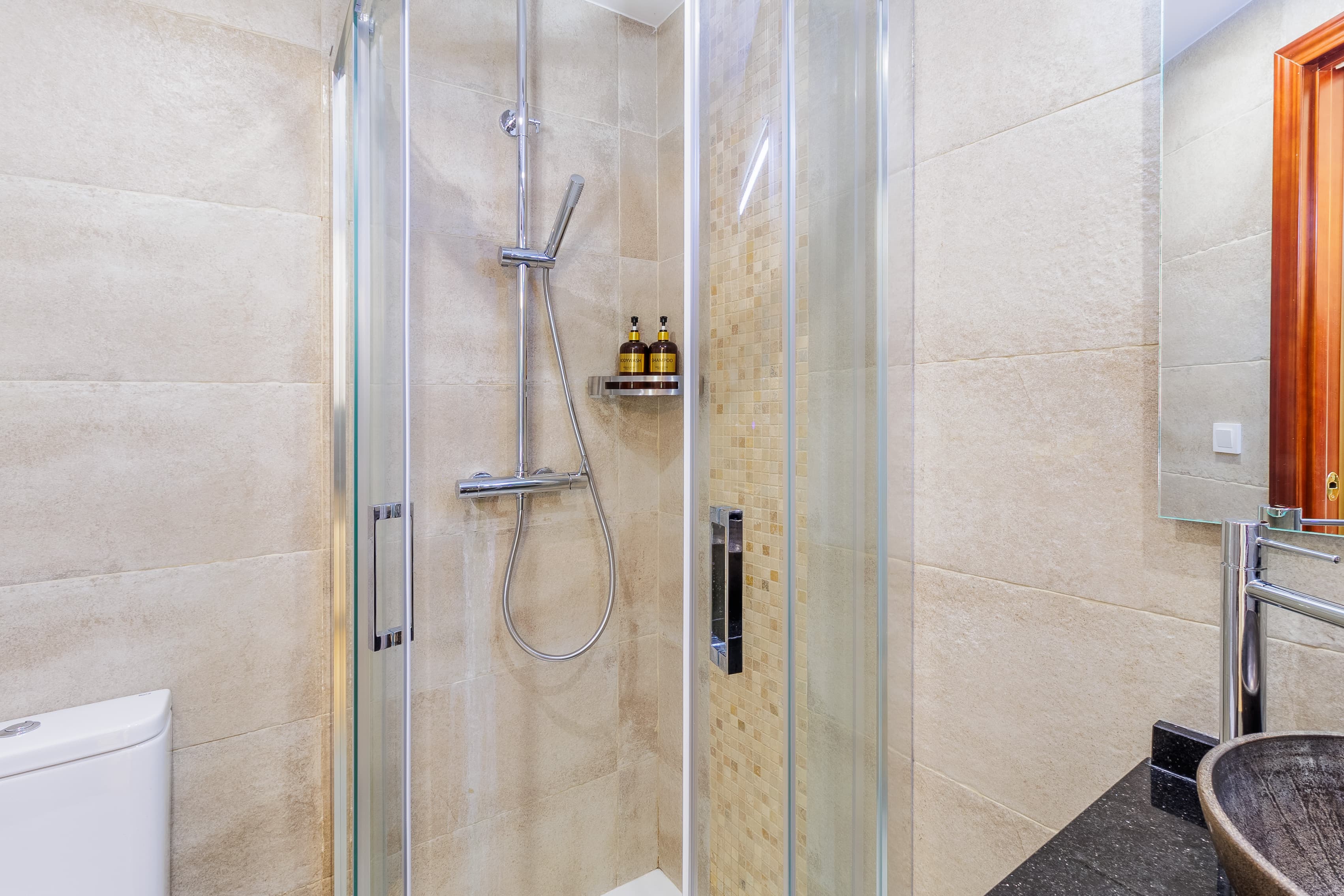 Second bathroom with a corner glass shower, mosaic tile accent, and a chrome rainfall shower fixture