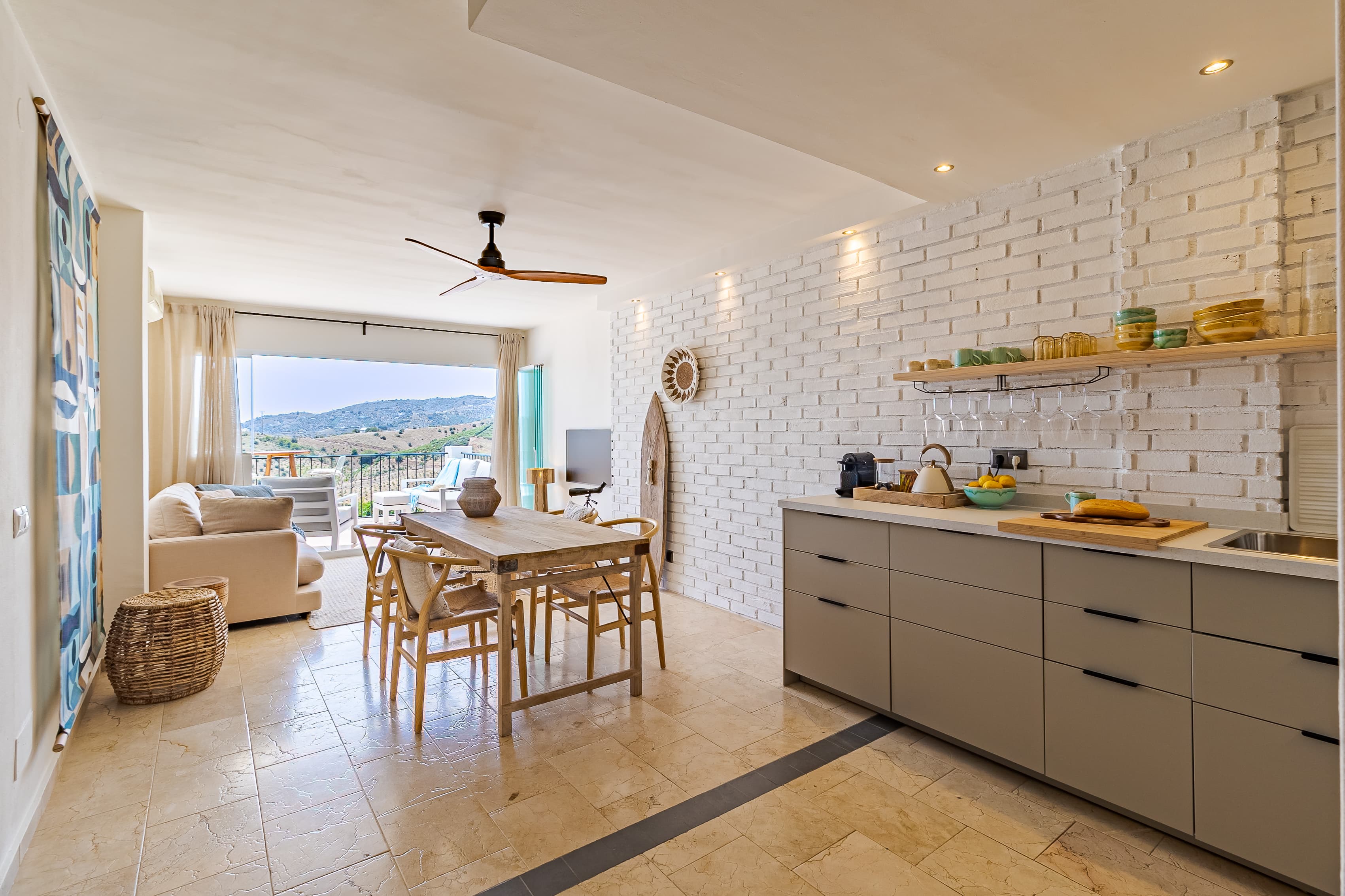 Kitchen and dining area viewed from the living room, with a surfboard wall decoration and mountain views beyond