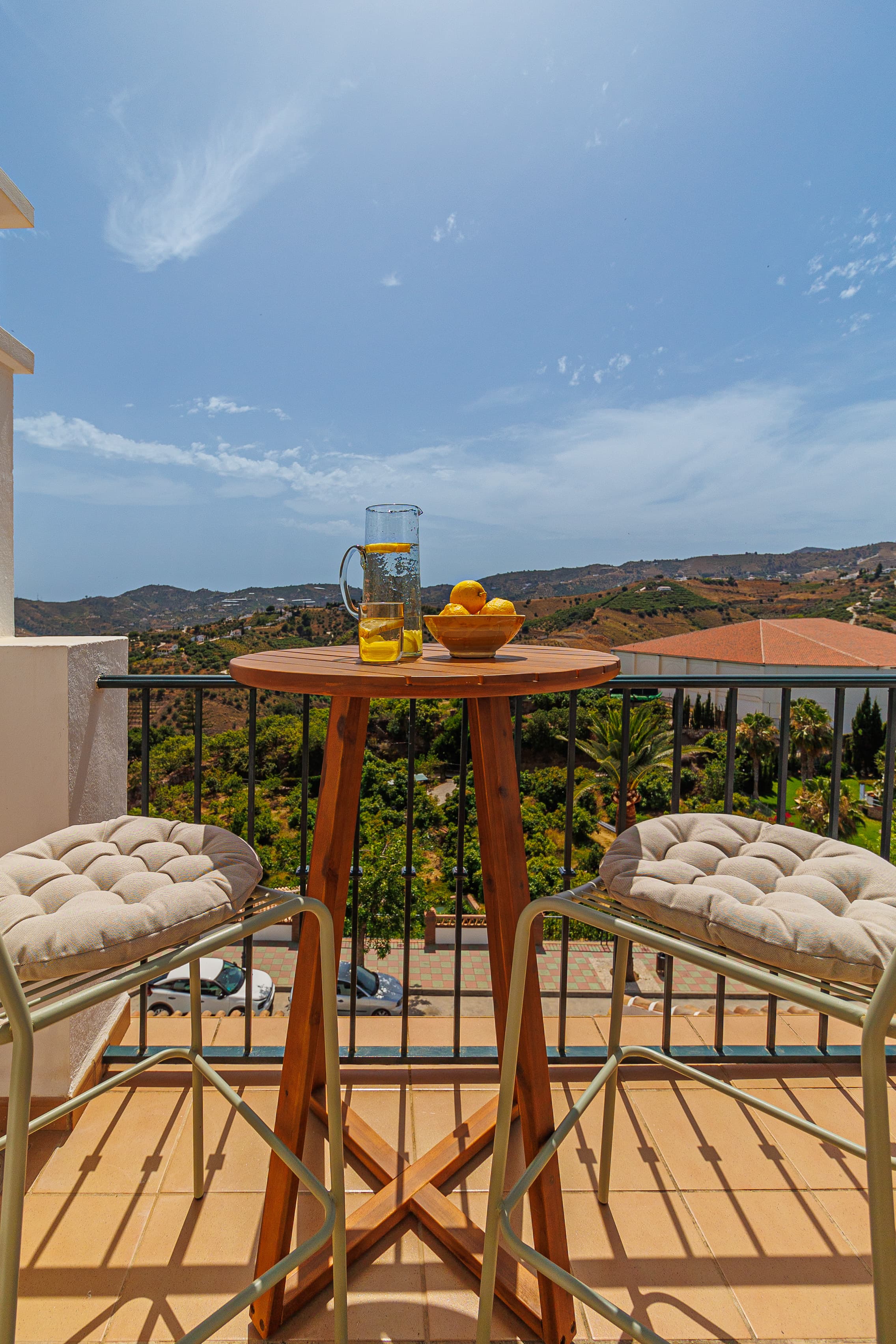 Balcony breakfast table with a lemonade pitcher, citrus bowl, and mountain views
