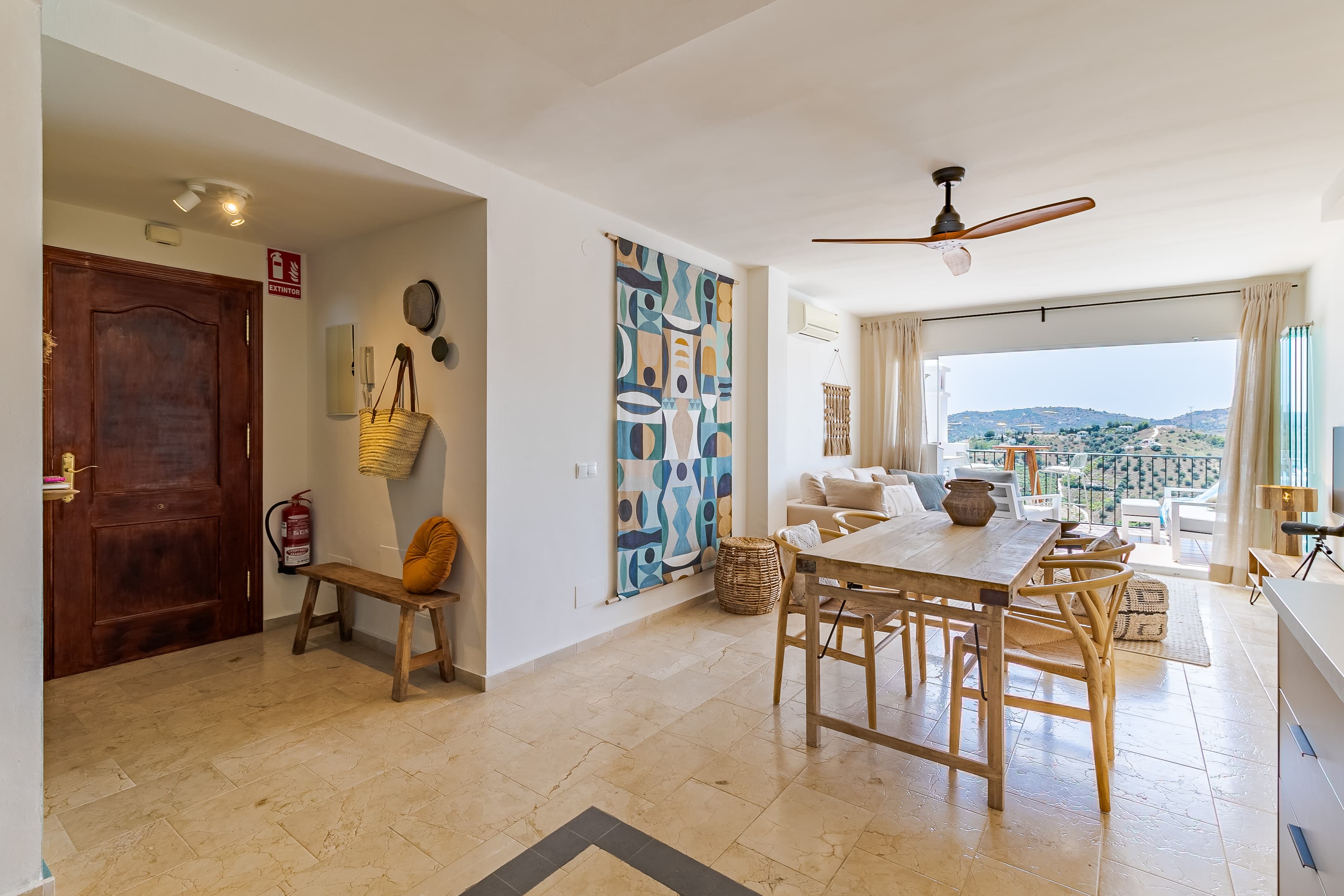 Open-plan living and dining area with colorful wall art and a terrace view