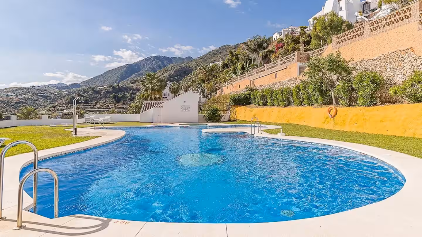 Communal swimming pool, second angle, with mountains and a yellow retaining wall