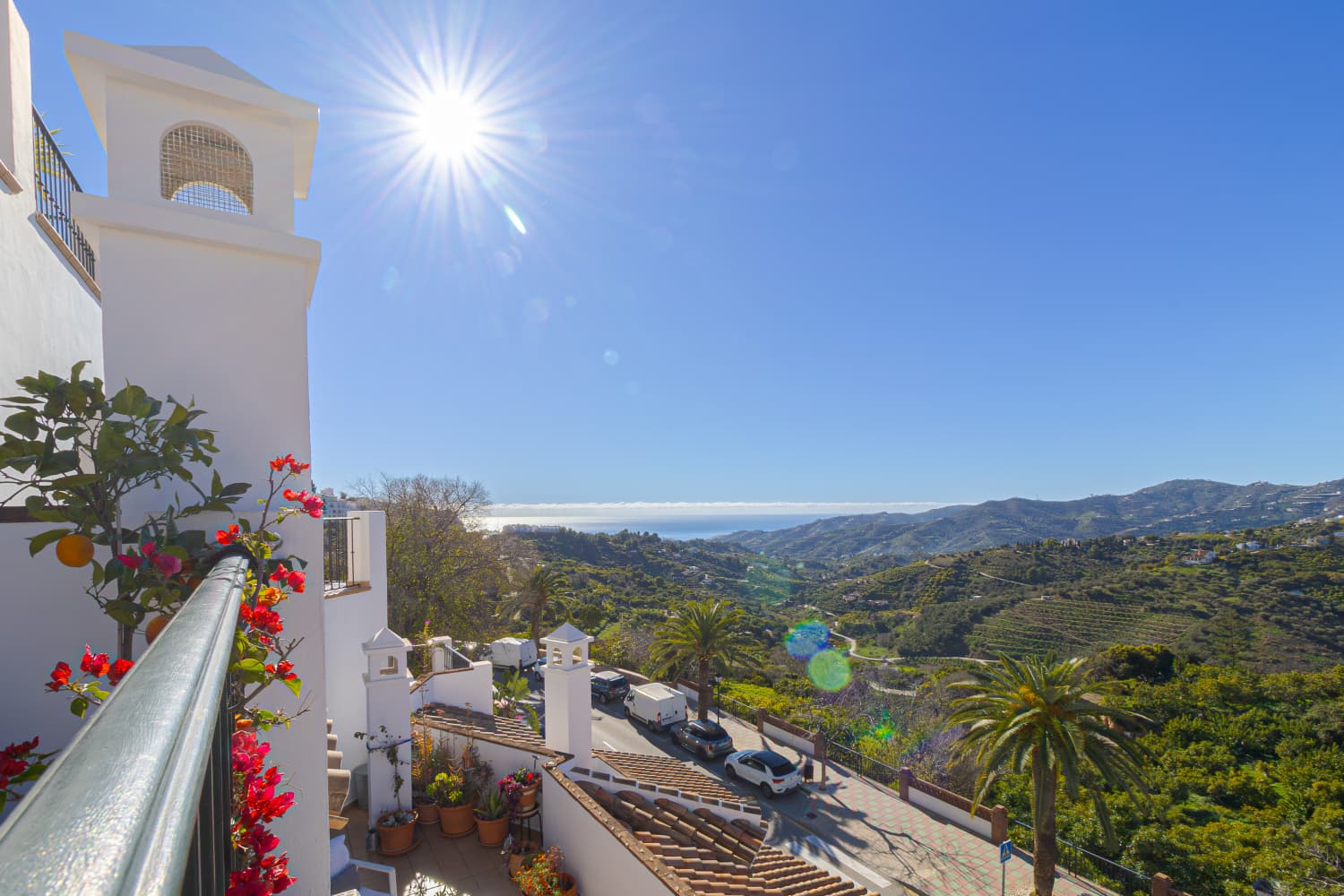 Sunlit balcony with sweeping sea and mountain views, bougainvillea in the foreground
